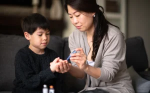 Mother helping son check blood sugar levels