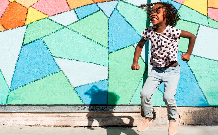 Girl dancing in front of colorful wall
