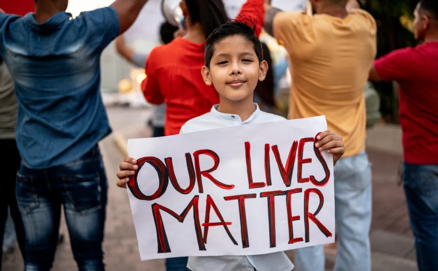 Portrait of child boy holding a sign on a protest outdoors