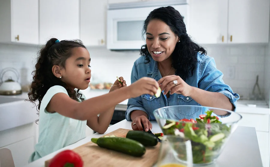 Mother and daughter preparing meal at home.